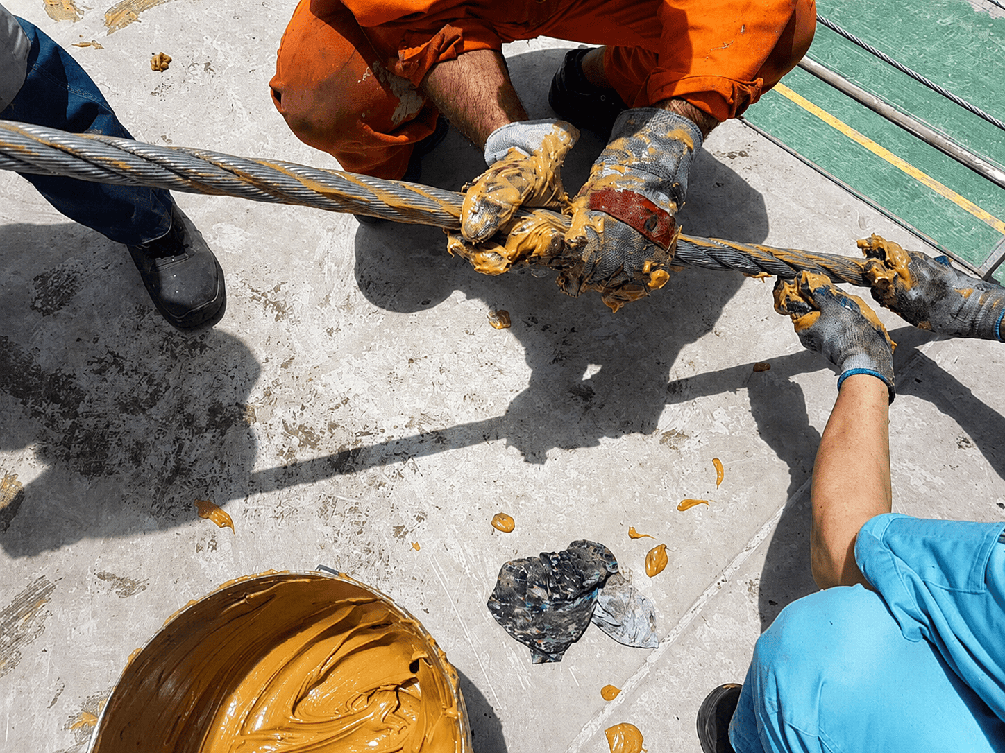 Workers applying lubricant to wire rope